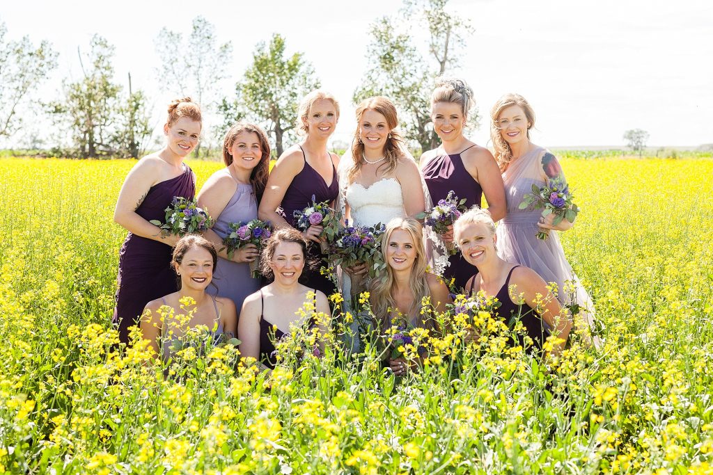 Bridal party in a canola field Rural farm wedding by Outdoor farmyard ceremony vows Getting ready Southern Alberta wedding photographer Kinsey Holt