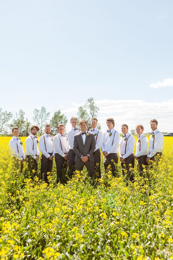 Bridal party in a canola field Rural farm wedding by Outdoor farmyard ceremony vows Getting ready Southern Alberta wedding photographer Kinsey Holt