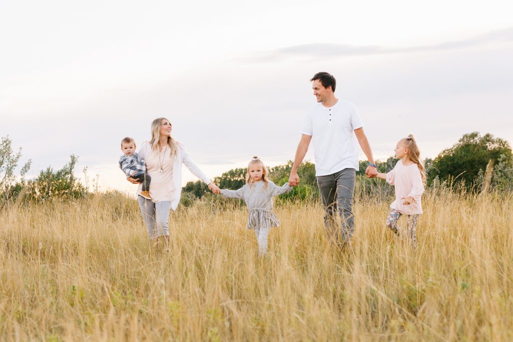 family walking through the grass for family photos in Magrath Alberta