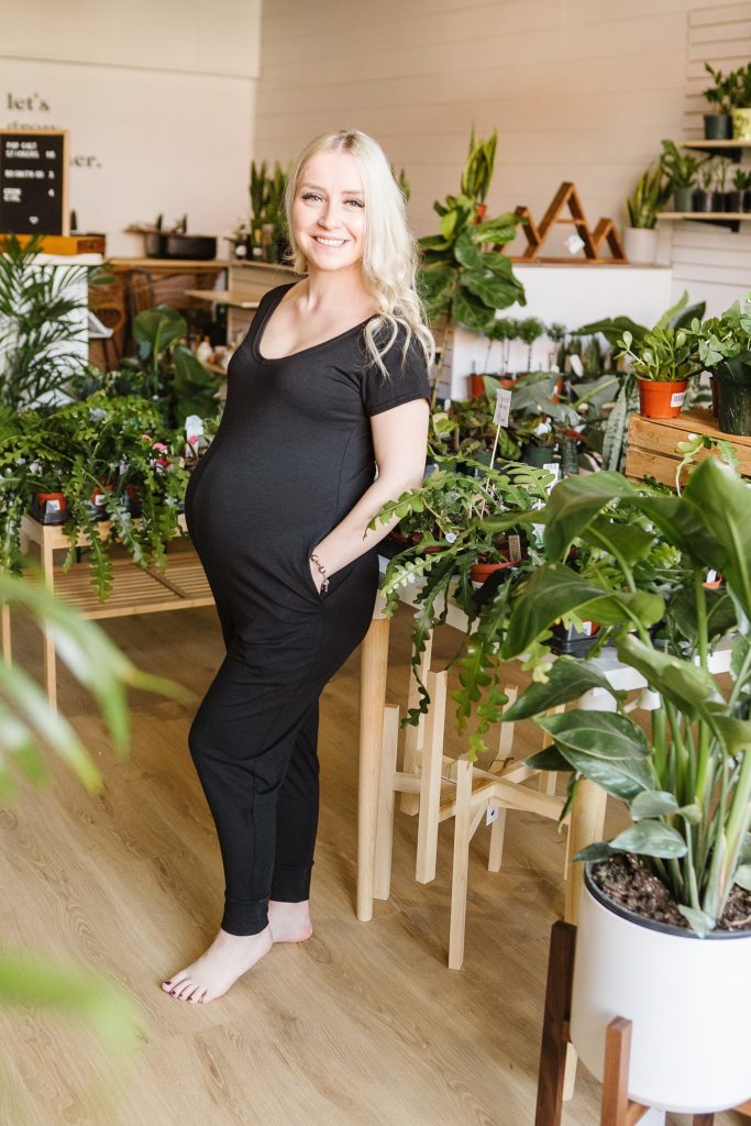 Pregnant model wearing black romper from 4 Fold Threads in plant store in Lethbridge, Alberta