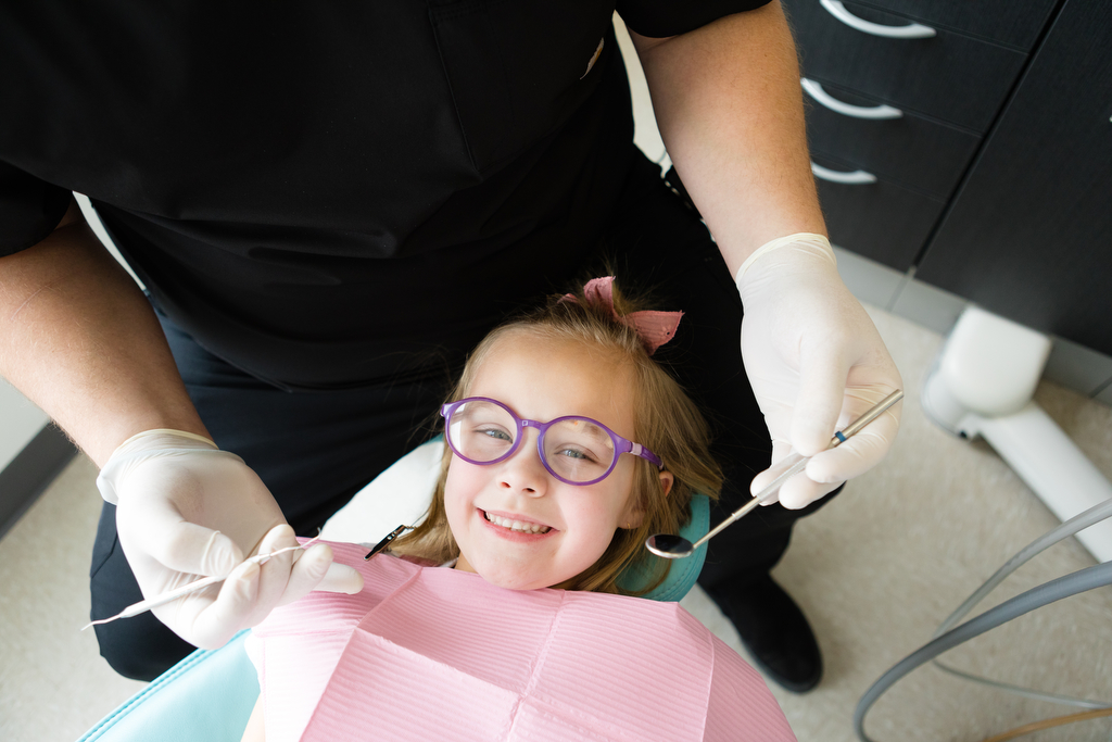 Smiling young girl with pink dental bib Lethbridge dentist photography