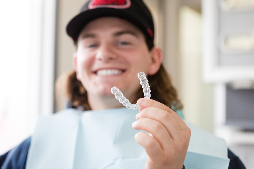 Young man holding up Invisalign trays - Lethbridge dentist photography