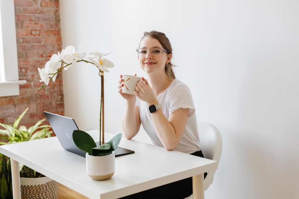 Woman sitting at a desk holding a mug. Shot by Lethbridge designer photographer Kinsey Holt.