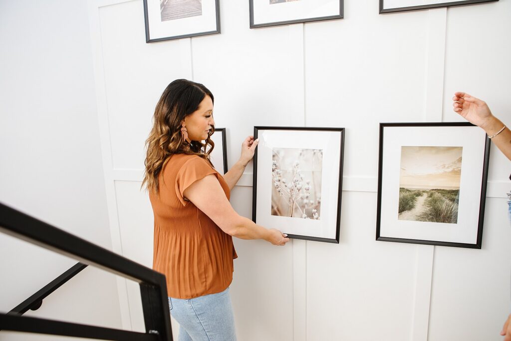 Woman adjusting a picture frame on the wall - Lethbridge brand photography by Kinsey Holt
