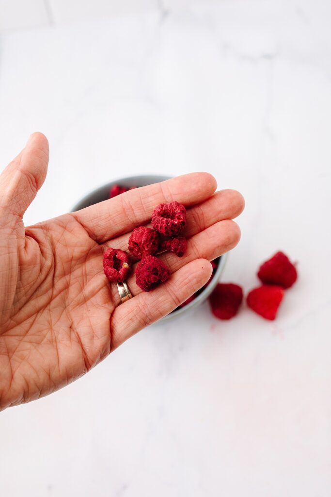 Hand holding freeze-dried raspberries. Shot by Kinsey Holt, Lethbridge food photographer. 